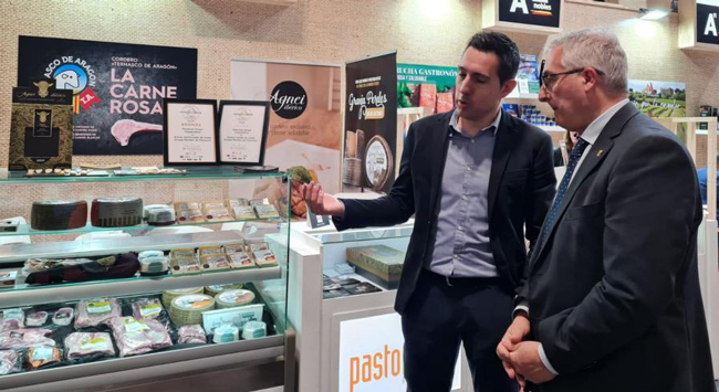 Dos hombres en traje hablando frente a un expositor de quesos en el Aragón Salón Gourmets
