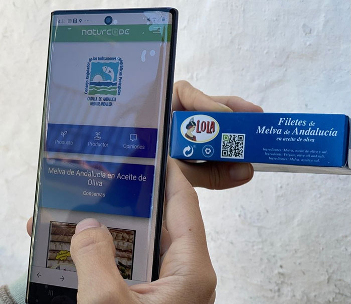 Hombre escanenado una caja de filetes de Melva de Andalucía con su móvil